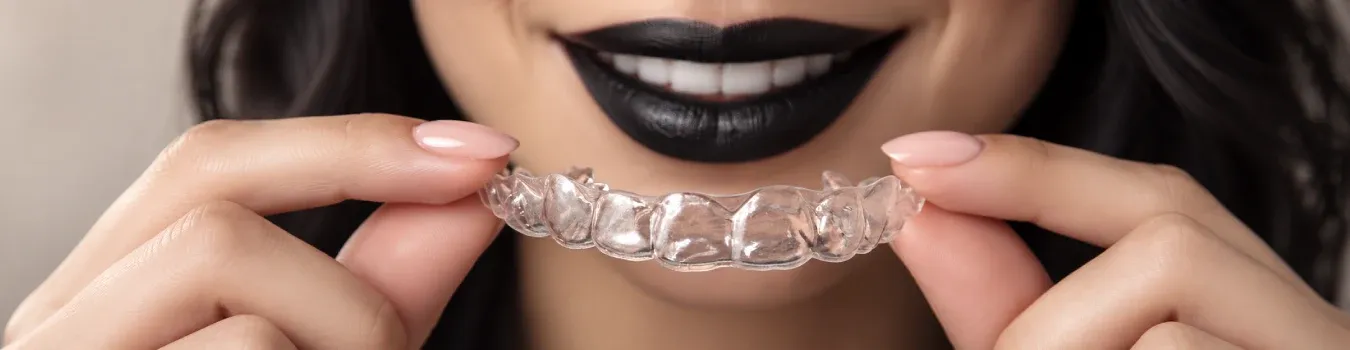 A woman holding a transparent dental aligner
