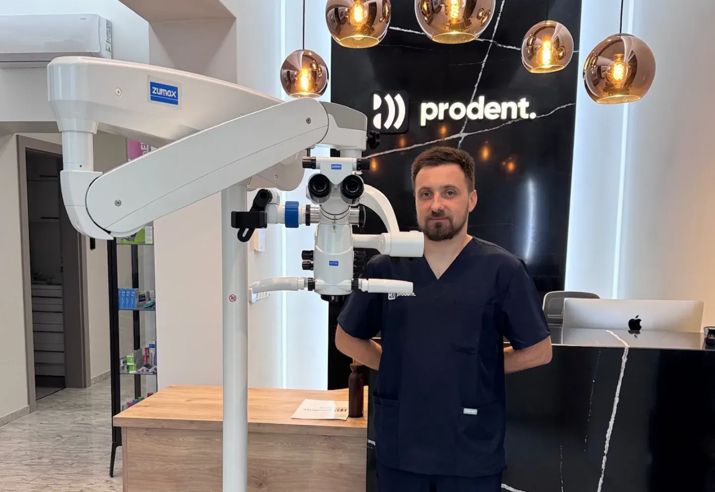 A clinician beside a Zumax dental microscope at ProDent